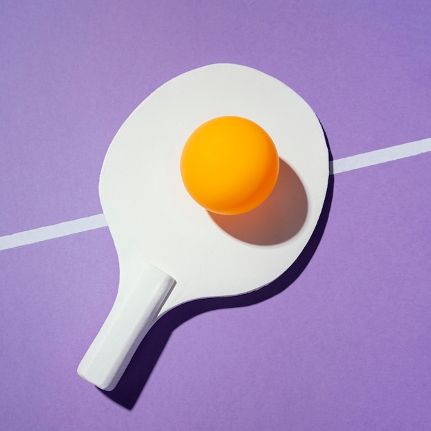 Bovenaanzicht gele bal op pingpongpeddel