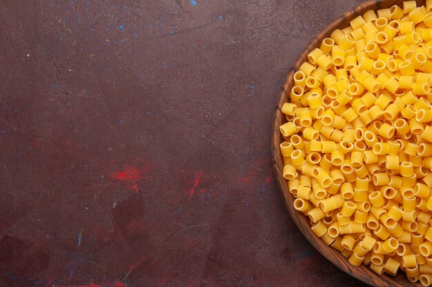 Bovenaanzicht gele italiaanse pasta rauw weinig gevormd op donkere achtergrond pasta eten rauwe deeg maaltijd