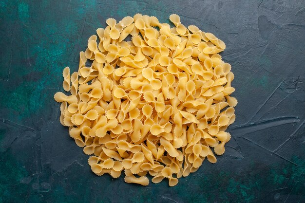Bovenaanzicht gele rauwe pasta Italiaanse pasta op de donkerblauwe achtergrond