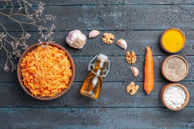 Bovenaanzicht geraspte wortelsalade met knoflook en kruiden op het donkerblauwe rustieke bureau gezondheid kleursalade rijp groentedieet