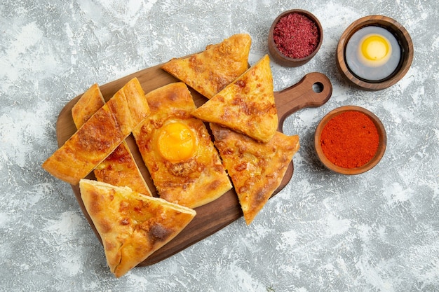 Gratis foto bovenaanzicht gesneden ei gebak gebakken brood met kruiden op een witte vloer gebak deeg voedsel maaltijd brood broodje