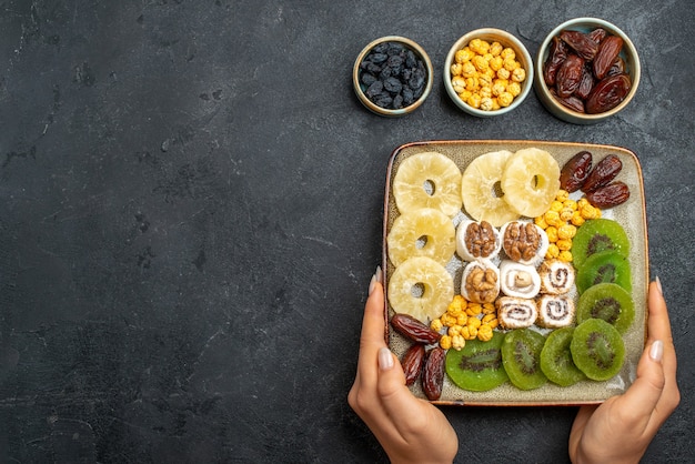 Gratis foto bovenaanzicht gesneden gedroogde vruchten ananasringen en kiwi's op een grijs bureau droog fruit rozijnen zoet vitamine zure gezondheid