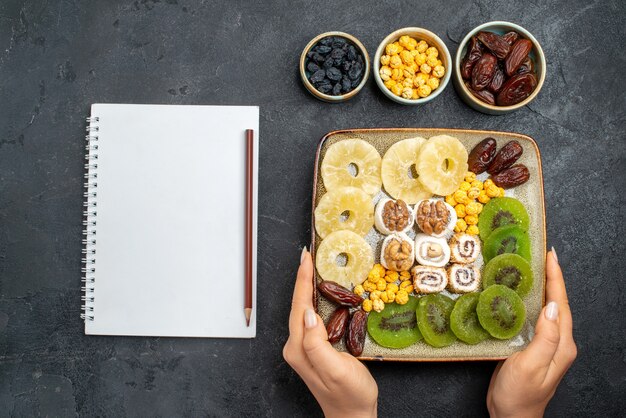 Bovenaanzicht gesneden gedroogde vruchten ananasringen en kiwi's op grijs bureau fruit rozijnen zoet vitamine zure gezondheid