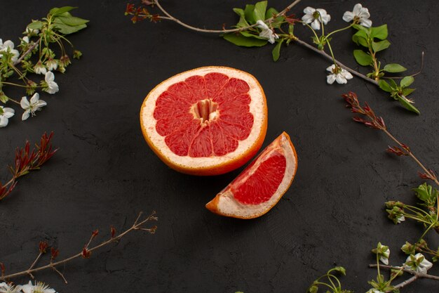 bovenaanzicht gesneden grapefruit mellow sappige rijp geïsoleerd samen met witte bloemen op de donkere achtergrond