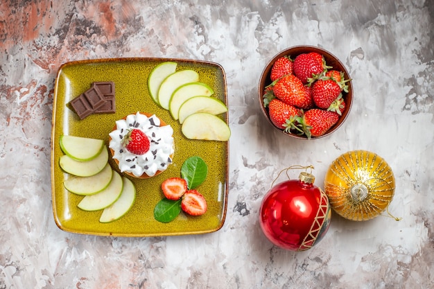 Bovenaanzicht gesneden groene appels met aardbeien en cake op lichte achtergrond