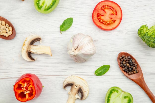 Bovenaanzicht gesneden groenten knoflook champignons houten lepels broccoli tomaat paprika op grijze tafel