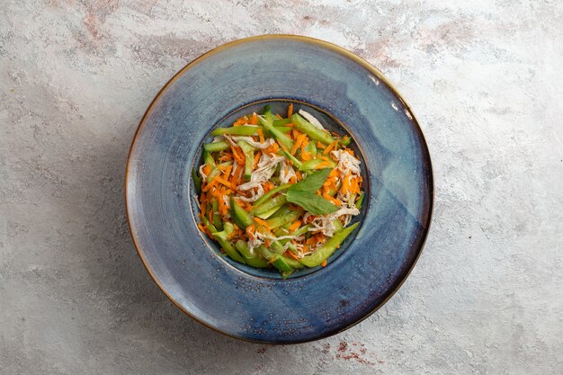 Bovenaanzicht gesneden groentesalade binnen plaat op lichte witte achtergrond