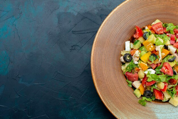 Bovenaanzicht gesneden groentesalade gepeperd binnen plaat op de donkerblauwe bureau salade groente voedsel maaltijd snack lunch