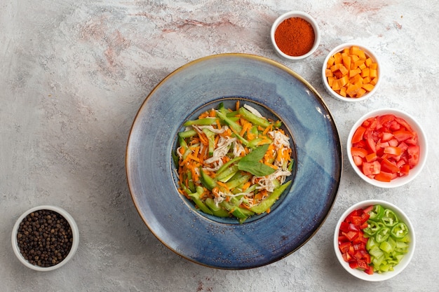 Gratis foto bovenaanzicht gesneden groentesalade met kruiden en andere gesneden groenten op de witte achtergrond