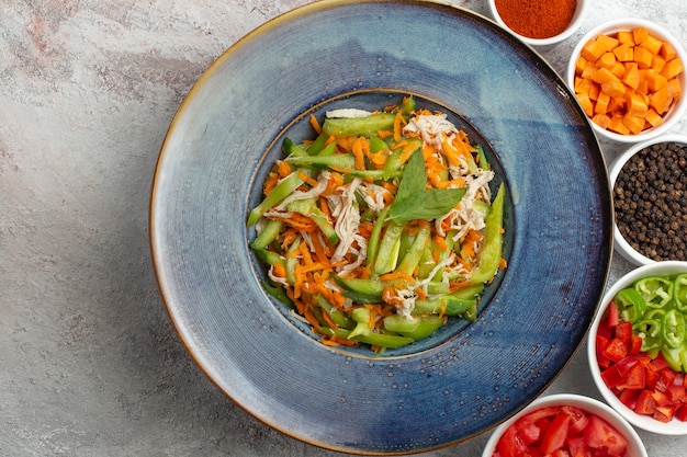 Bovenaanzicht gesneden groentesalade met kruiden op witte achtergrond