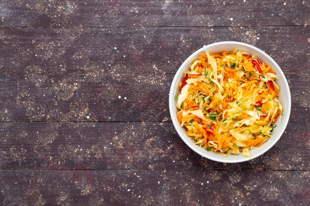 Bovenaanzicht gesneden groentesalade vers en gezouten binnen plaat op het bruine bureau plantaardige voedsel maaltijd schotel verse foto