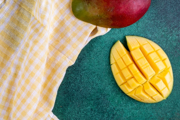 Gratis foto bovenaanzicht gesneden mango met een gele keuken handdoek op groen