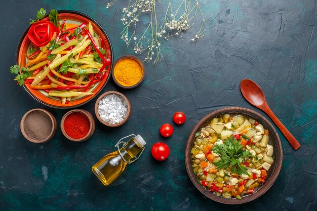 Bovenaanzicht gesneden paprika gezonde salade met olijfoliesoep en kruiden op donkerblauw bureau