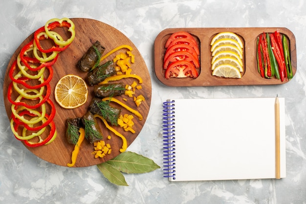 Bovenaanzicht gesneden paprika met blad dolma en groenten op wit bureau