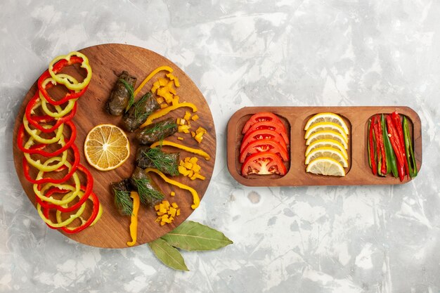 Bovenaanzicht gesneden paprika met heerlijke blad dolma en groenten op wit bureau