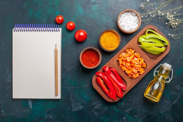 Bovenaanzicht gesneden paprika met kruiden en olie op de donkerblauwe achtergrond