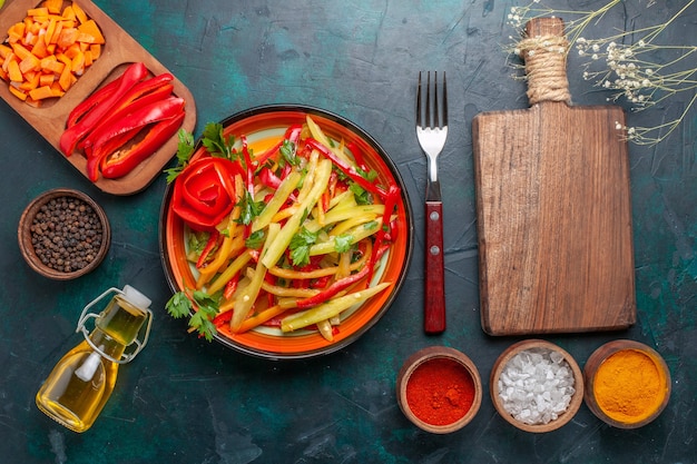 Bovenaanzicht gesneden paprika met kruiden salade en olie op donkerblauw bureau