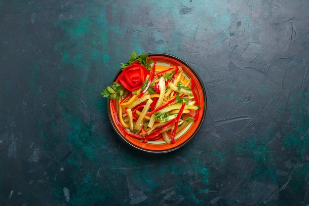 Bovenaanzicht gesneden paprika verschillende gekleurde groentesalade binnen plaat op de donkerblauwe achtergrond