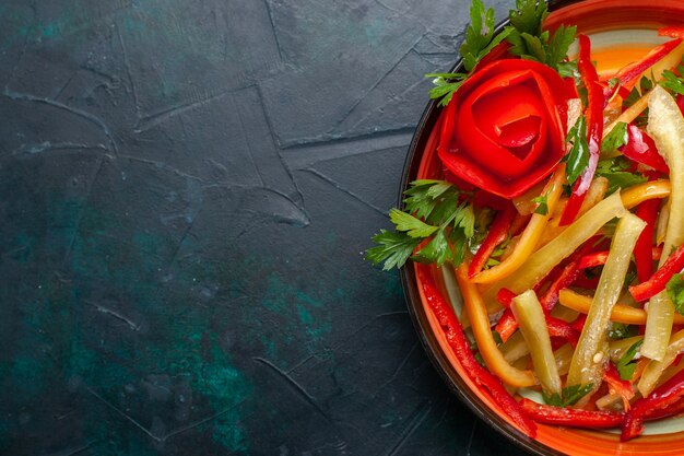 Bovenaanzicht gesneden paprika verschillende gekleurde salade binnen plaat op donkere ondergrond