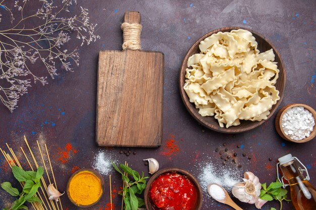 Bovenaanzicht gesneden rauw deeg met kruiden op donkere achtergrond deeg pasta eten diner maaltijd