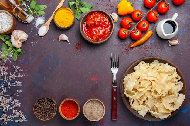 Bovenaanzicht gesneden rauw deeg met verschillende kruiden op donkere achtergrond maaltijd diner pastadeeg