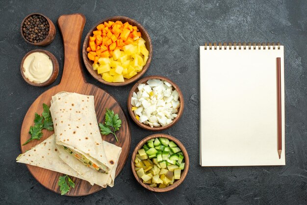 Bovenaanzicht gesneden shaurma smakelijke salade sandwich met groenten op het grijze oppervlak hamburger pita sandwich salade brood