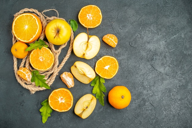 Bovenaanzicht gesneden sinaasappelen en appels op donkere achtergrond