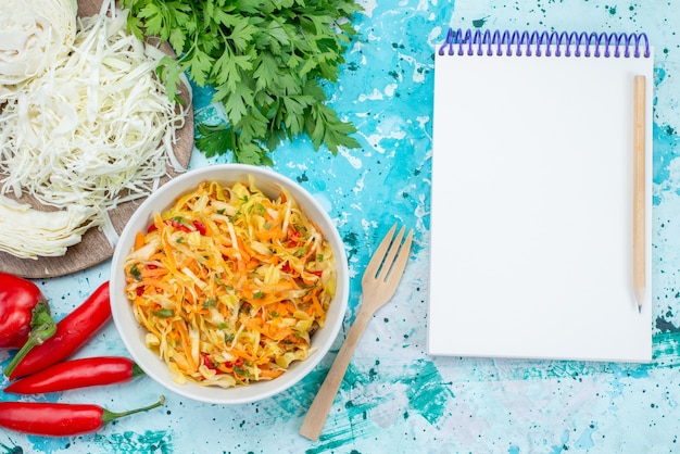 Bovenaanzicht gesneden verse groenten lange en dunne stukjes salade binnen plaat met groene kool paprika op de helderblauwe achtergrond voedsel maaltijd groenten salade