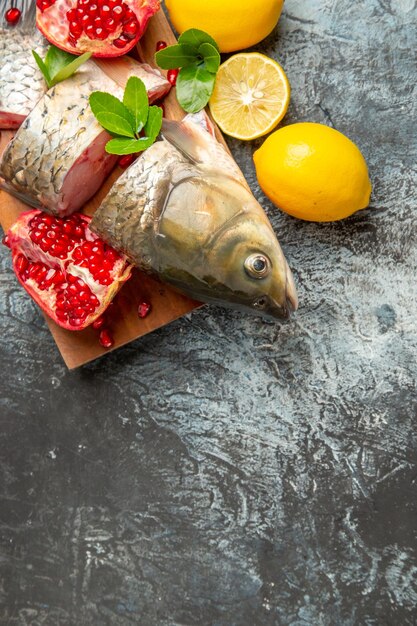 Bovenaanzicht gesneden verse vis met granaatappels en citroen op lichte ondergrond