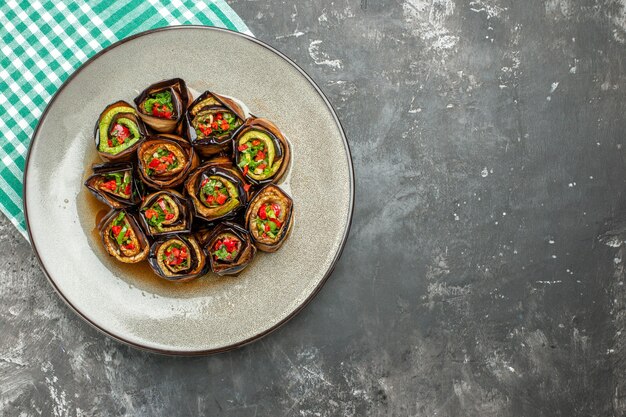 Bovenaanzicht gevulde auberginebroodjes in wit ovaal bord turquoise-wit tafelkleed op grijs oppervlak