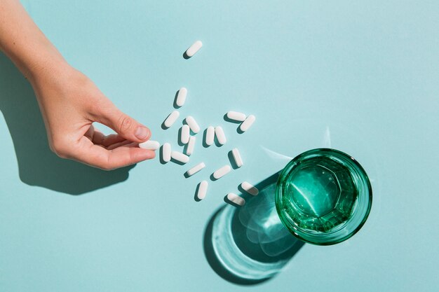 Bovenaanzicht glas met water en medicijnen op tafel