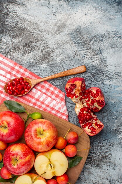 Bovenaanzicht granaatappel granaatappel lepel appels kersen op het bord op het tafellaken