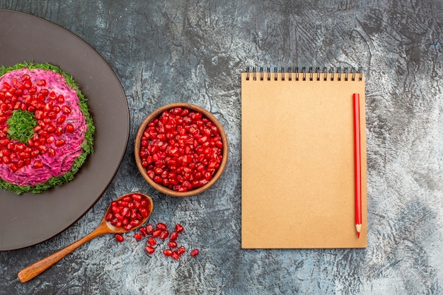 Bovenaanzicht granaatappels een smakelijke schotel kom met granaatappel zaden notebook potlood