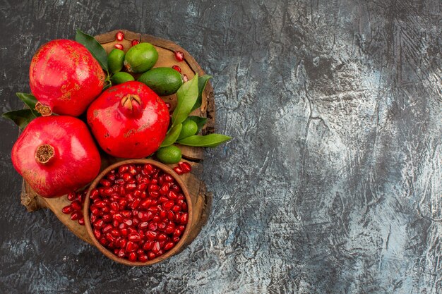 Bovenaanzicht granaatappels zaden van granaatappel in kom drie granaatappels op het keukenbord