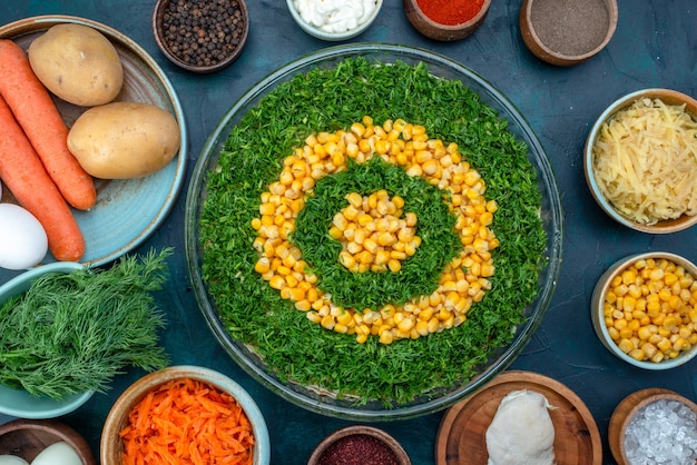 Bovenaanzicht greens salade met likdoorns samen met kruiden en eieren op de donkerblauwe achtergrond.