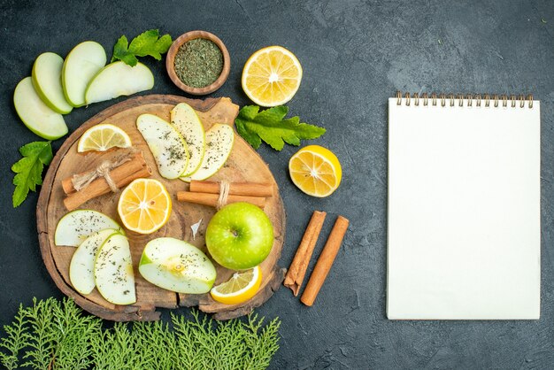 Bovenaanzicht groene appel kaneelstokjes appel en citroen schijfjes op een houten bord