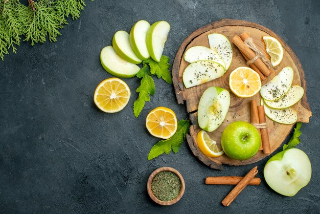 Bovenaanzicht groene appels, kaneelstokjes en schijfjes citroen, appelschijfjes op een houten bord