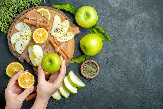 Bovenaanzicht groene appels, kaneelstokjes en schijfjes citroen, appelschijfjes op een houten bord