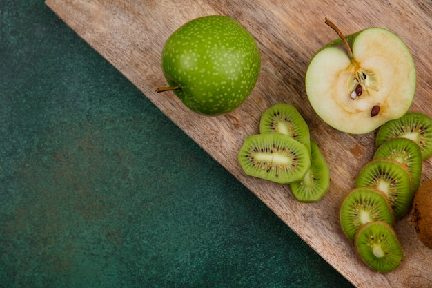 Bovenaanzicht groene appels met kiwiplakken op bord op groene achtergrond