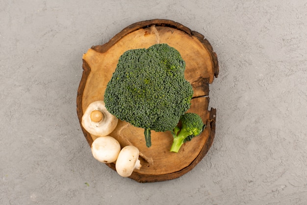 Bovenaanzicht groene broccoli samen met champignons op de grijze vloer