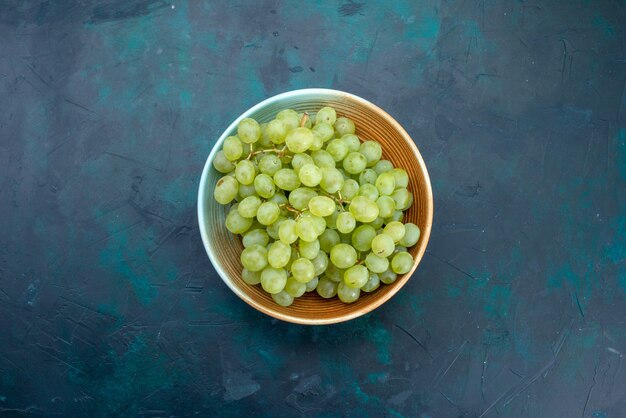 Bovenaanzicht groene druiven in dienblad op donker