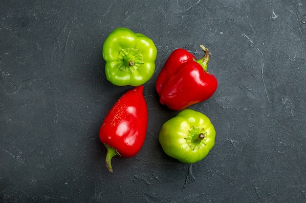 Bovenaanzicht groene en rode paprika's op donkere vrije ruimte