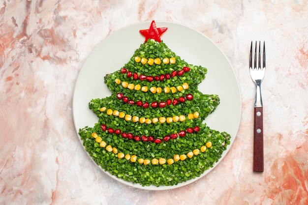 Bovenaanzicht groene salade in de vorm van een nieuwjaarsboom in de plaat op de lichte achtergrond