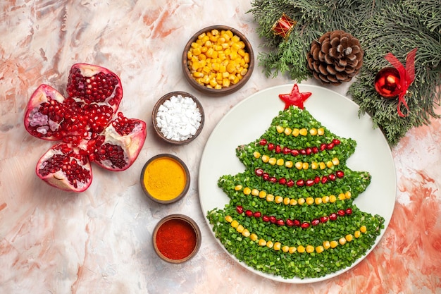 Bovenaanzicht groene salade in kerstboomvorm met kruiden op lichte achtergrond