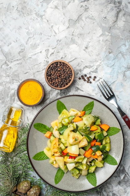 Bovenaanzicht groene tomatensalade op ovale plaat een vorkkruidenoliefles op donkere achtergrond