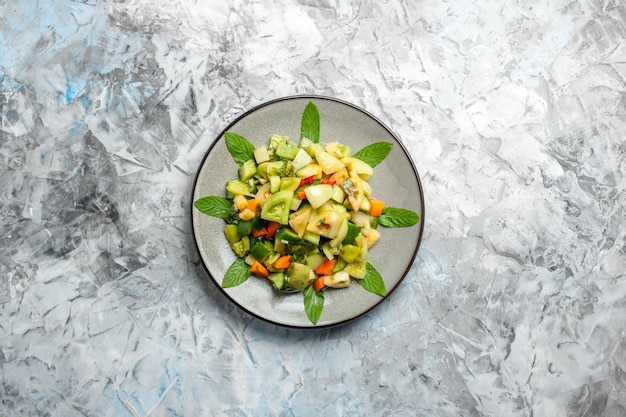 Bovenaanzicht groene tomatensalade op ovale plaat op grijze achtergrond