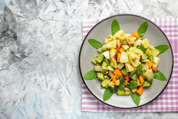 Bovenaanzicht groene tomatensalade op ovale plaat op roze servet op donkere achtergrond