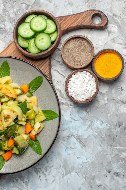 Bovenaanzicht groene tomatensalade op ovale plaat op snijplank op donkere achtergrond