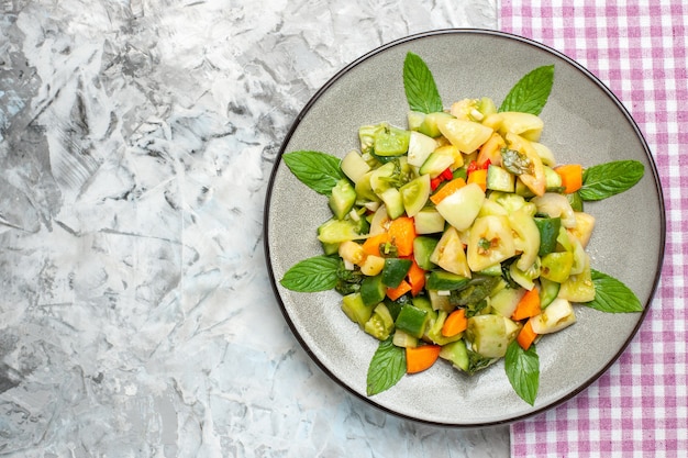 Bovenaanzicht groene tomatensalade op ovale plaat roze tafelkleed op donkere achtergrond vrije ruimte