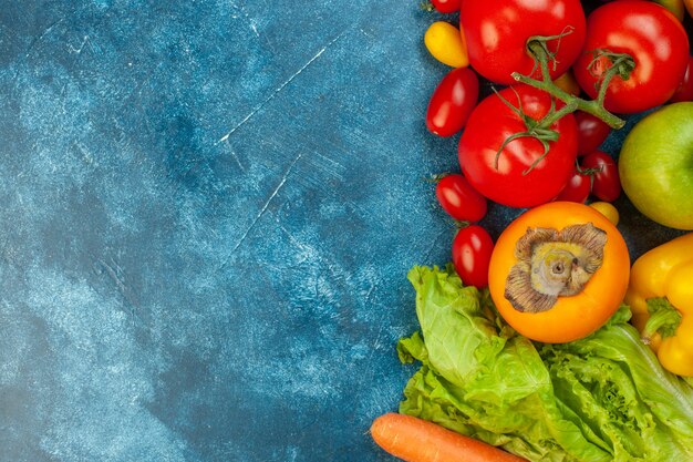 Bovenaanzicht groenten en fruit cherrytomaatjes cumcuat tomaten sla persimmon op blauwe tafel